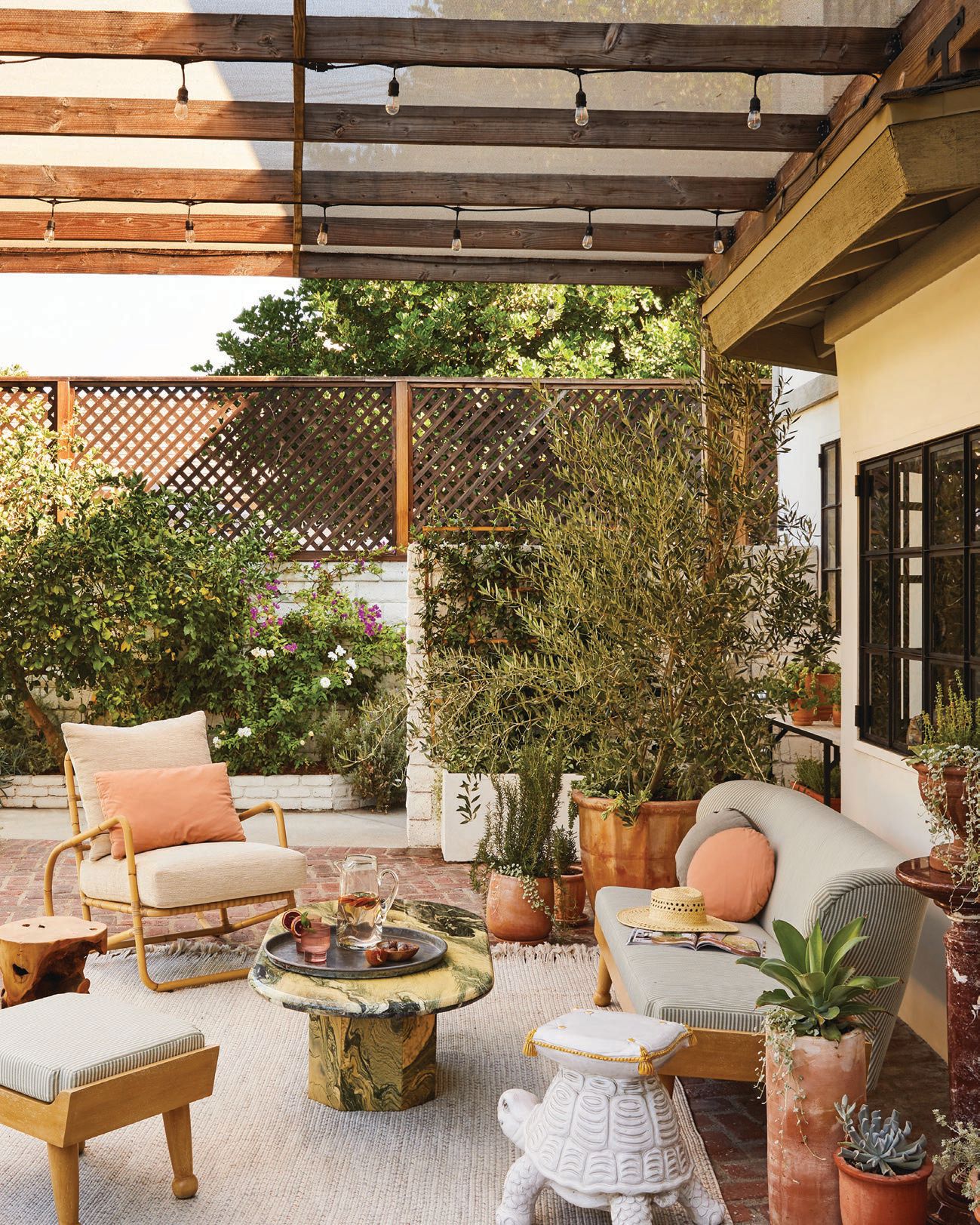 The patio contains a mix of new and vintage pieces, including a sofa and ottoman from August Abode’s Hayworth Collection, a vintage Italian marble coffee table from the 1960s found at Castle Antiques & Design and a vintage terra-cotta turtle garden stool from Van den Andern found on 1stDibs. Photographed By Sam Frost
